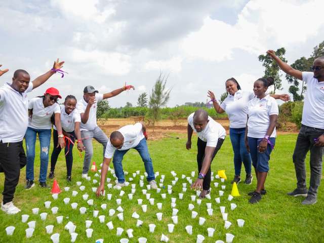 A team cheering as teammates race through a cup challenge on the lawn