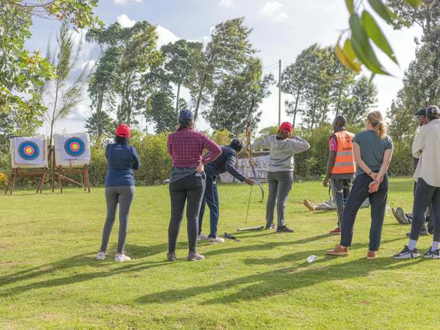 A guest drawing a bow at targets with an instructor watching