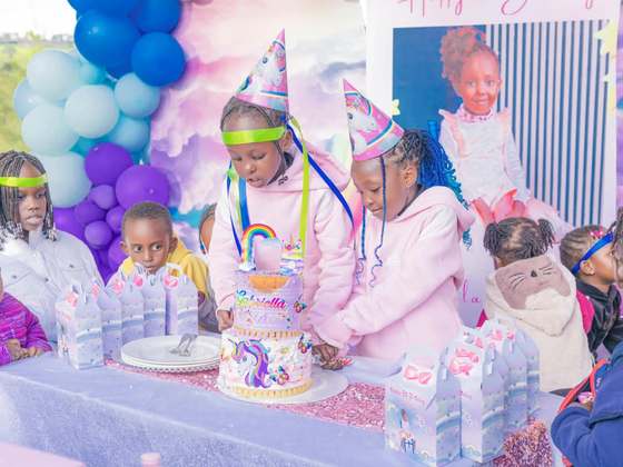 Children cutting a unicorn birthday cake at a party