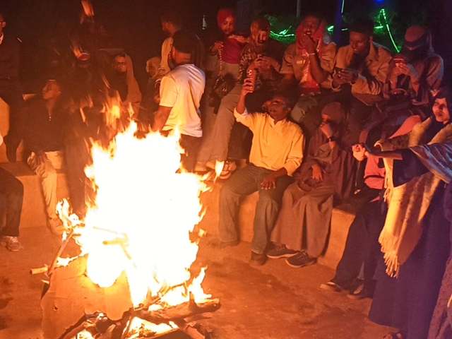 Guests laughing around the evening bonfire at the park
