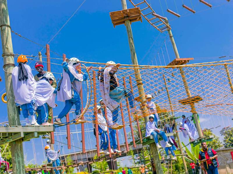 Guests in helmets crossing a rope net on the Burudani high ropes course
