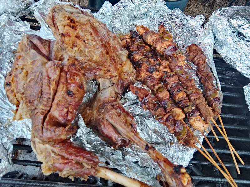 Roast goat leg and skewers of nyama choma on the charcoal grill