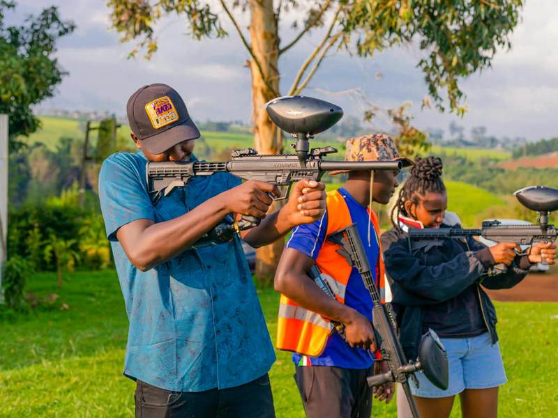 Guests aiming paintball markers at targets on the lawn